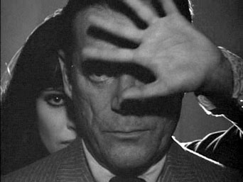 Screenshot d'Alphaville : Natasha Von Braun (Anna Karina) derrire Lemmy Caution (Eddie Constantine)